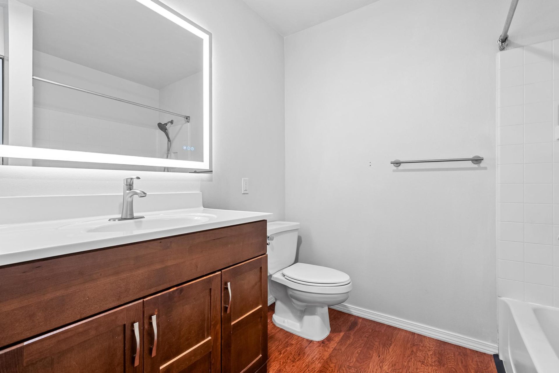 Primary en-suite bath with backlit LED mirror and wood vanity