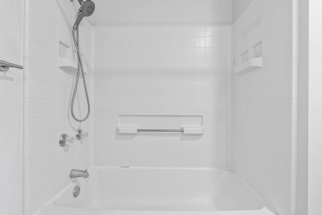 Primary bath tub and shower with white tile surround